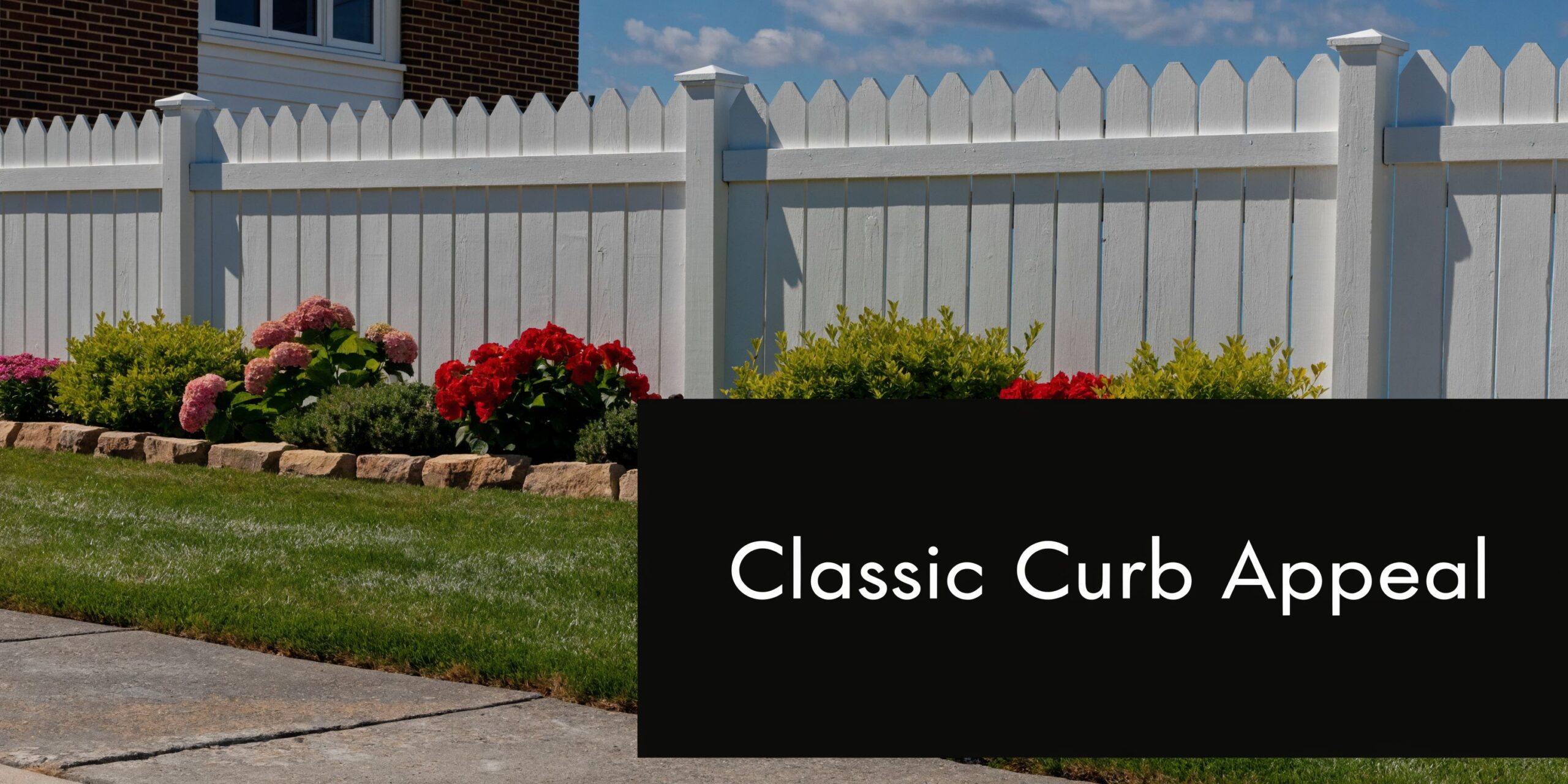 A classic white picket fence borders a lush green lawn with vibrant red and pink hydrangea flowers.